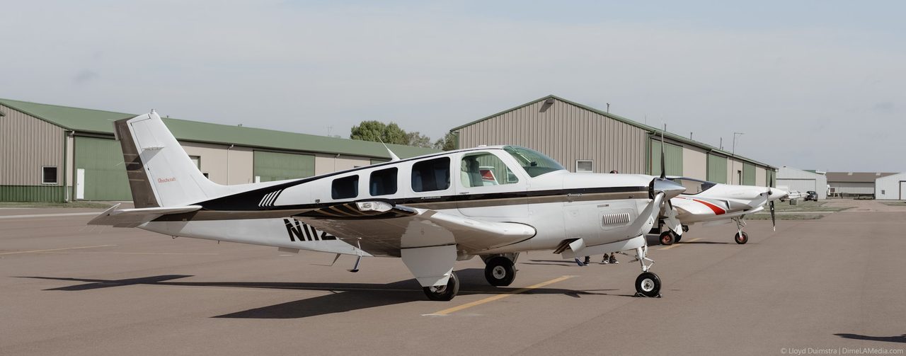 Beechcraft Bonanza aircraft parked on the ramp outside a hangar