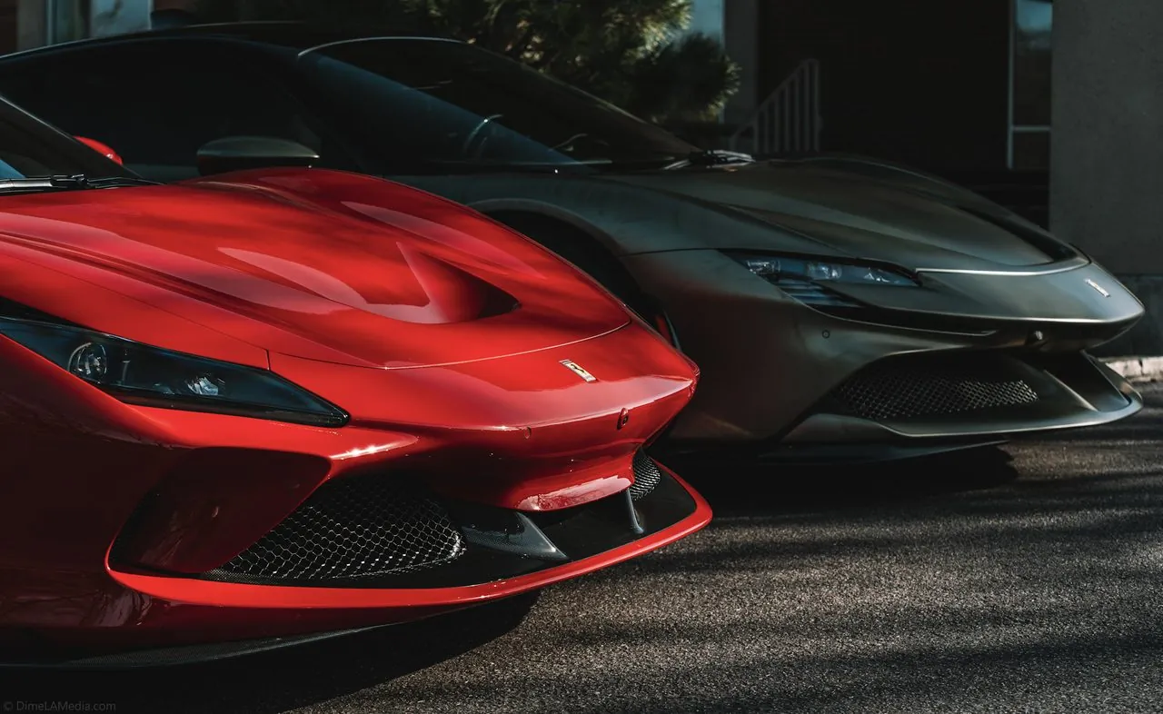 Red Ferrari F8 and matte grey Ferrari parked nose to nose at a dealership