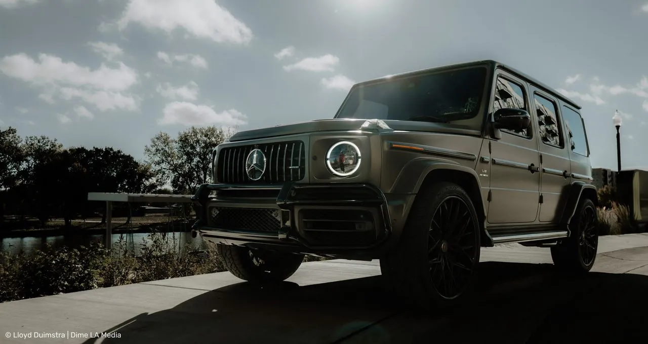 Mercedes-AMG G63 in matte grey backlit by the sun near a river path