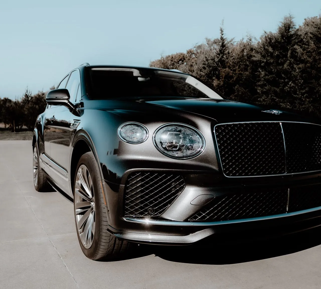 Black Bentley Bentayga front three-quarter on a concrete driveway