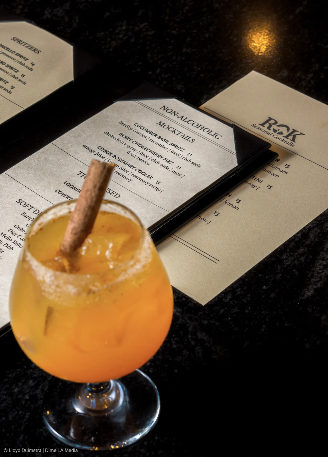 Amber fall cocktail with a cinnamon stick next to a non-alcoholic mocktail menu