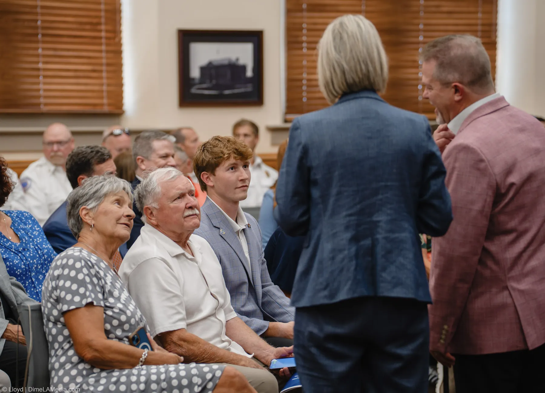 Christine Erickson visits with seated family members in the chamber before the ceremony