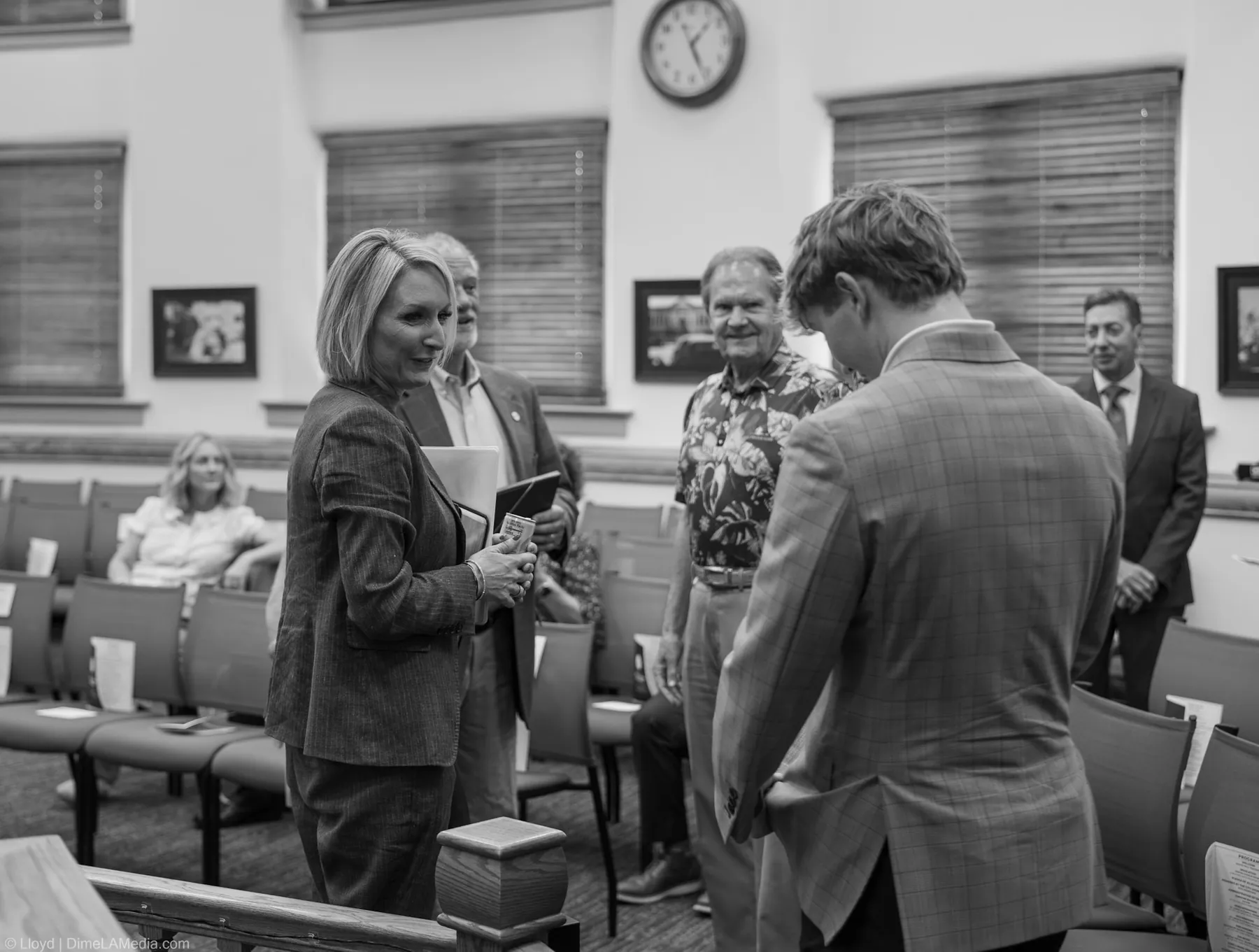 Black and white frame of Christine Erickson greeting guests inside the council chamber at Carnegie Town Hall before her swearing-in