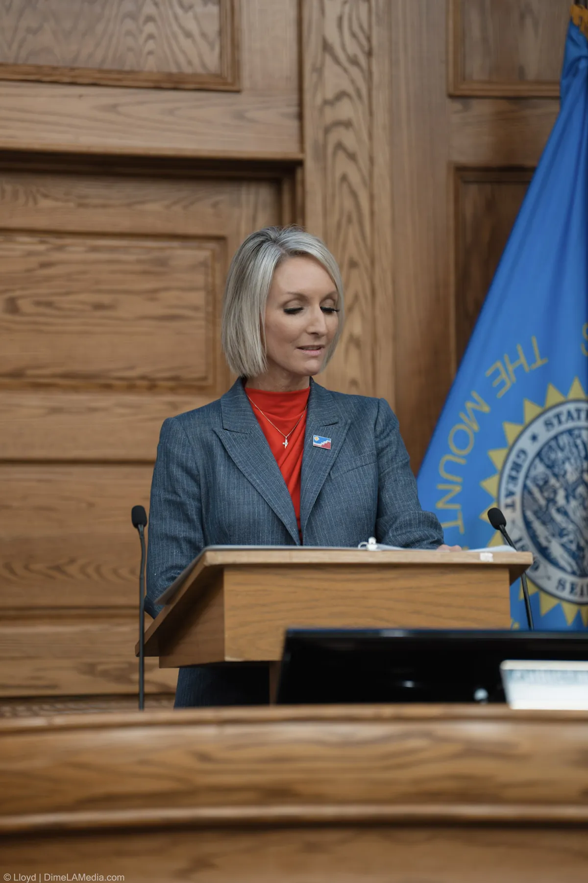 Mayor Christine Erickson pauses at the podium beside the South Dakota flag during her remarks