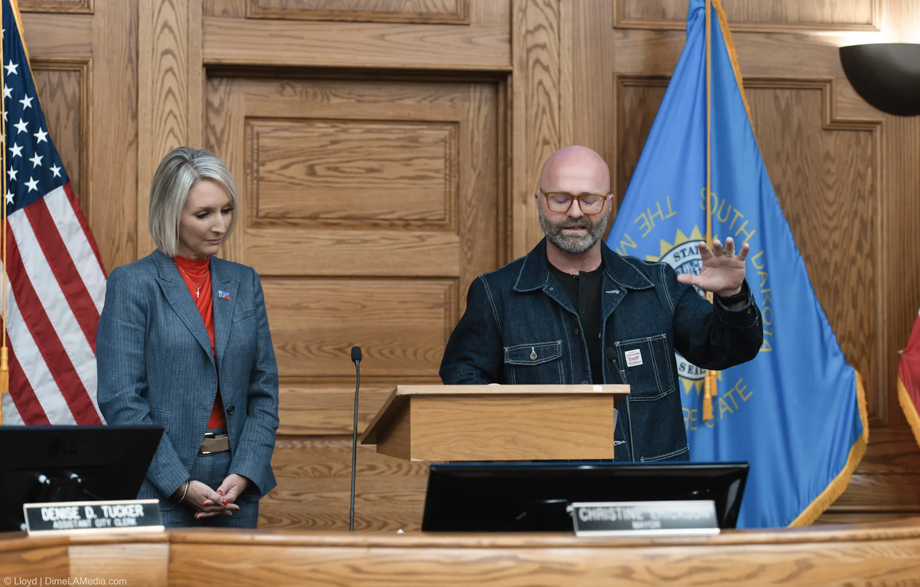 Pastor Adam Weber extends a hand in blessing as Mayor Christine Erickson stands with head bowed