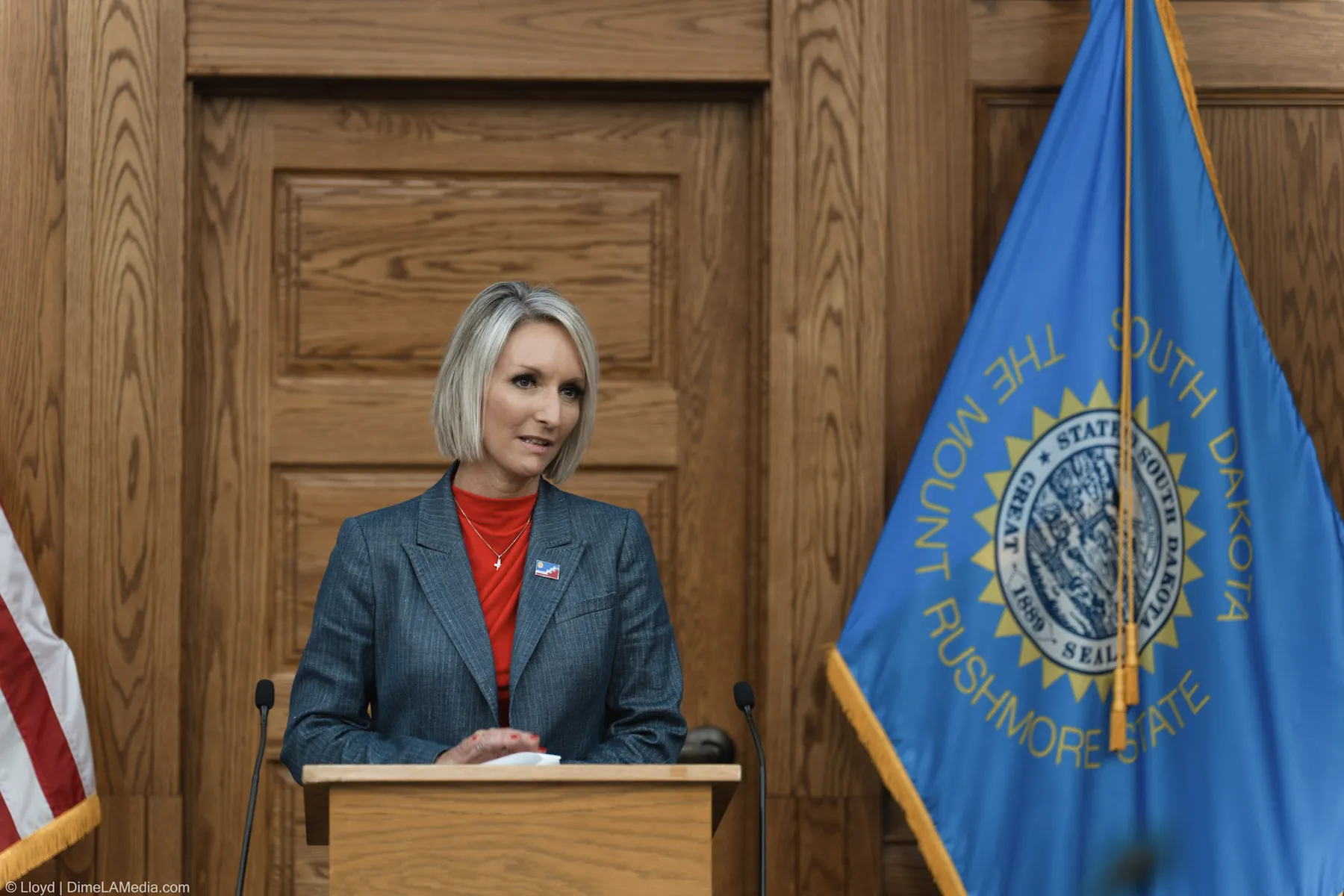 Mayor Christine Erickson speaks at the podium beside the South Dakota state flag