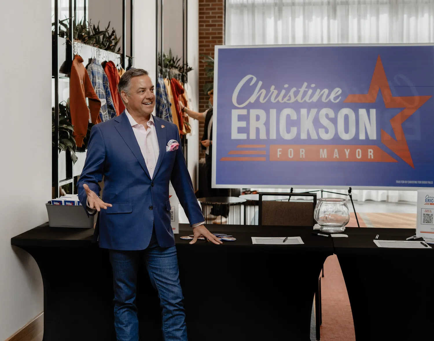 A supporter speaks beside the Christine Erickson for Mayor sign at a campaign event
