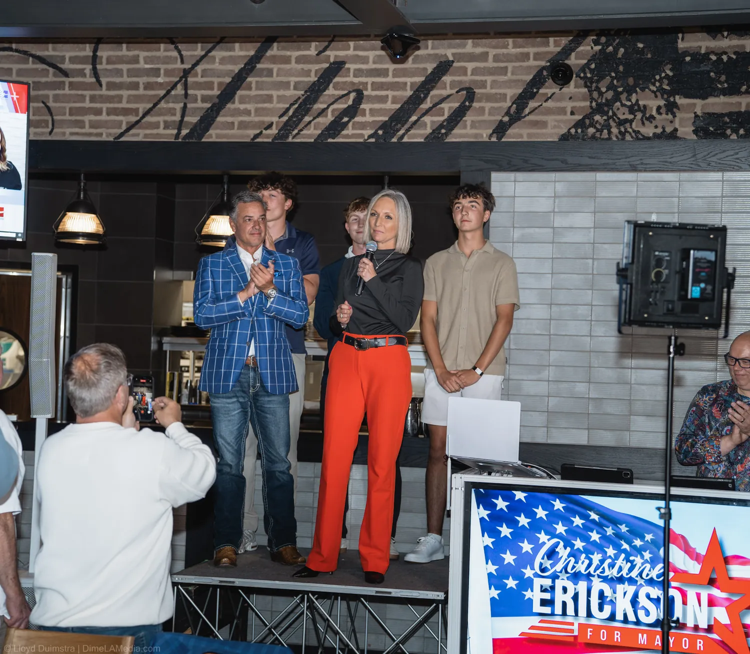 Wide view of Christine Erickson delivering her victory speech beside her campaign sign