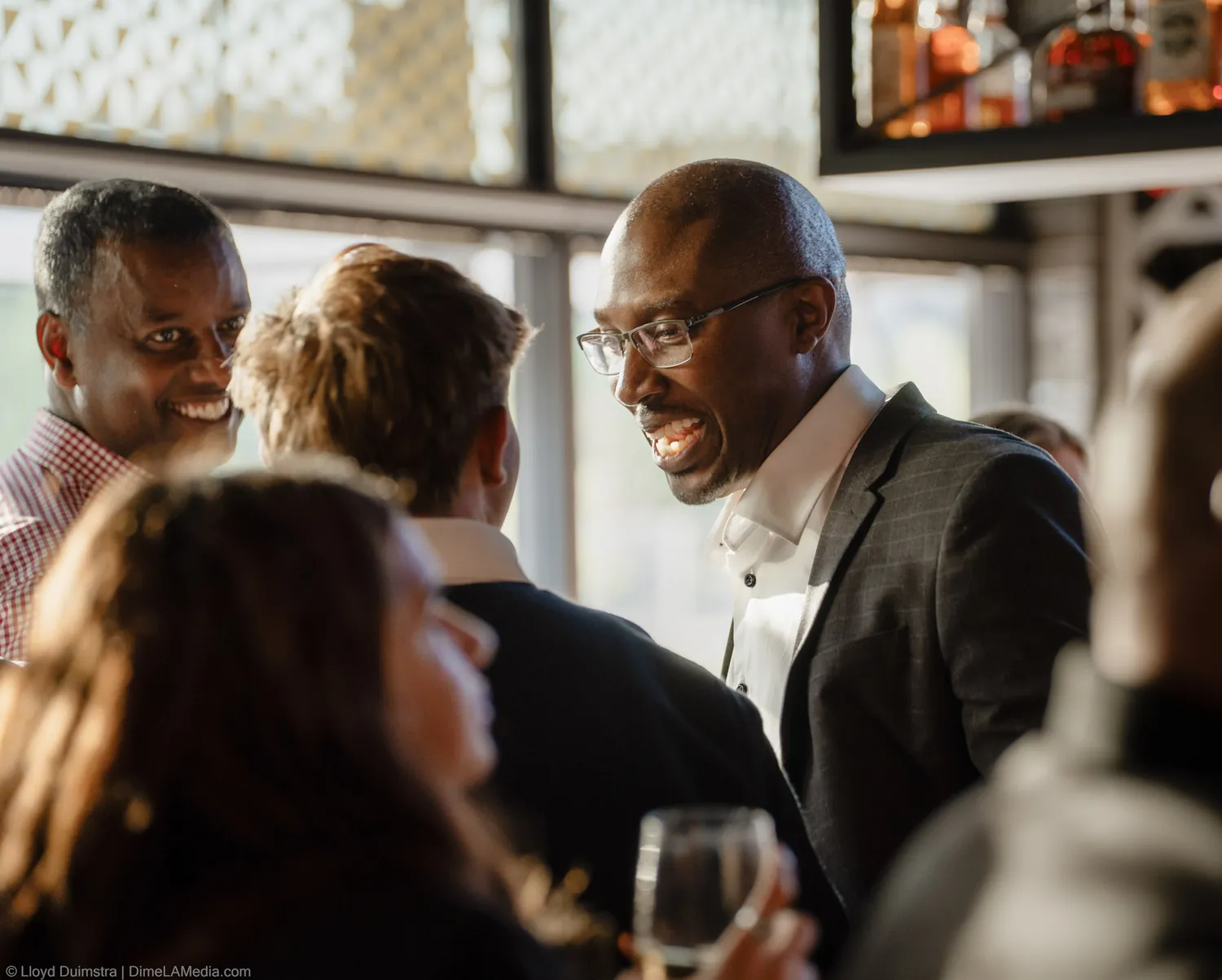 The watch party crowd mingles in warm evening light before the results arrive