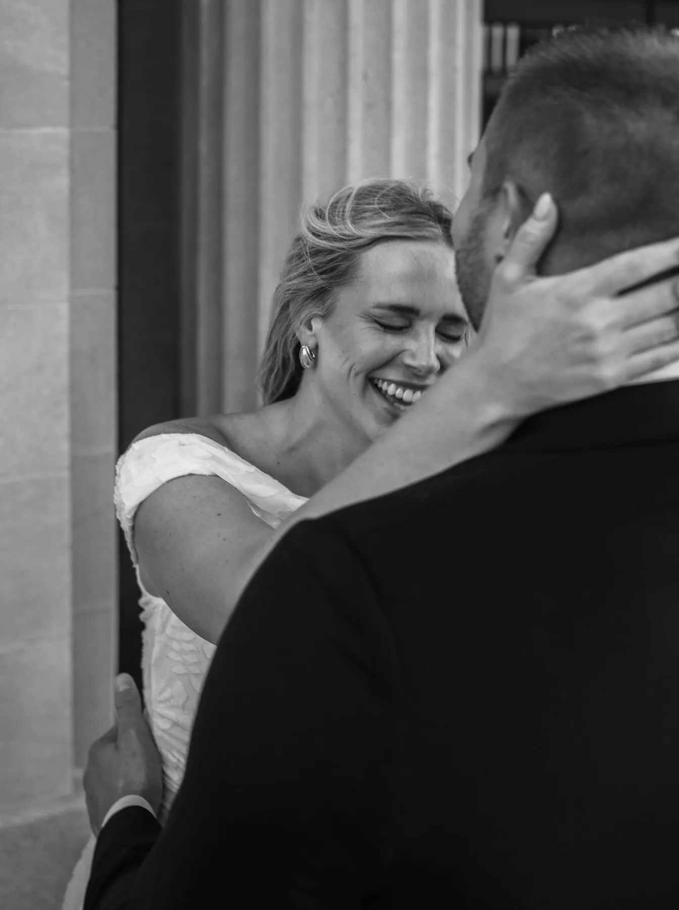 Bride-to-be laughing into her fiance's shoulder, black and white