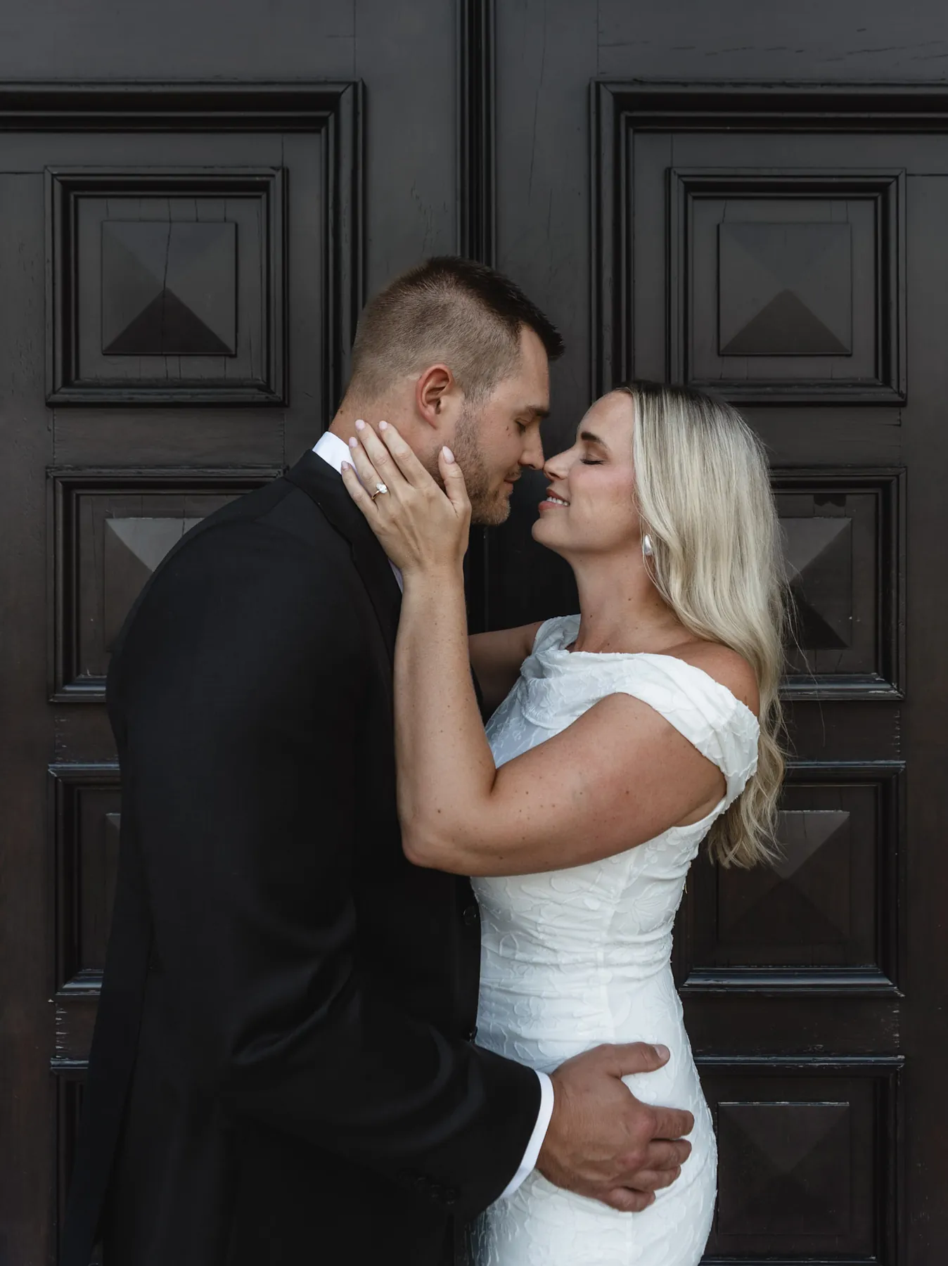 Engaged couple kissing in front of the carved cathedral doors, Sioux Falls SD