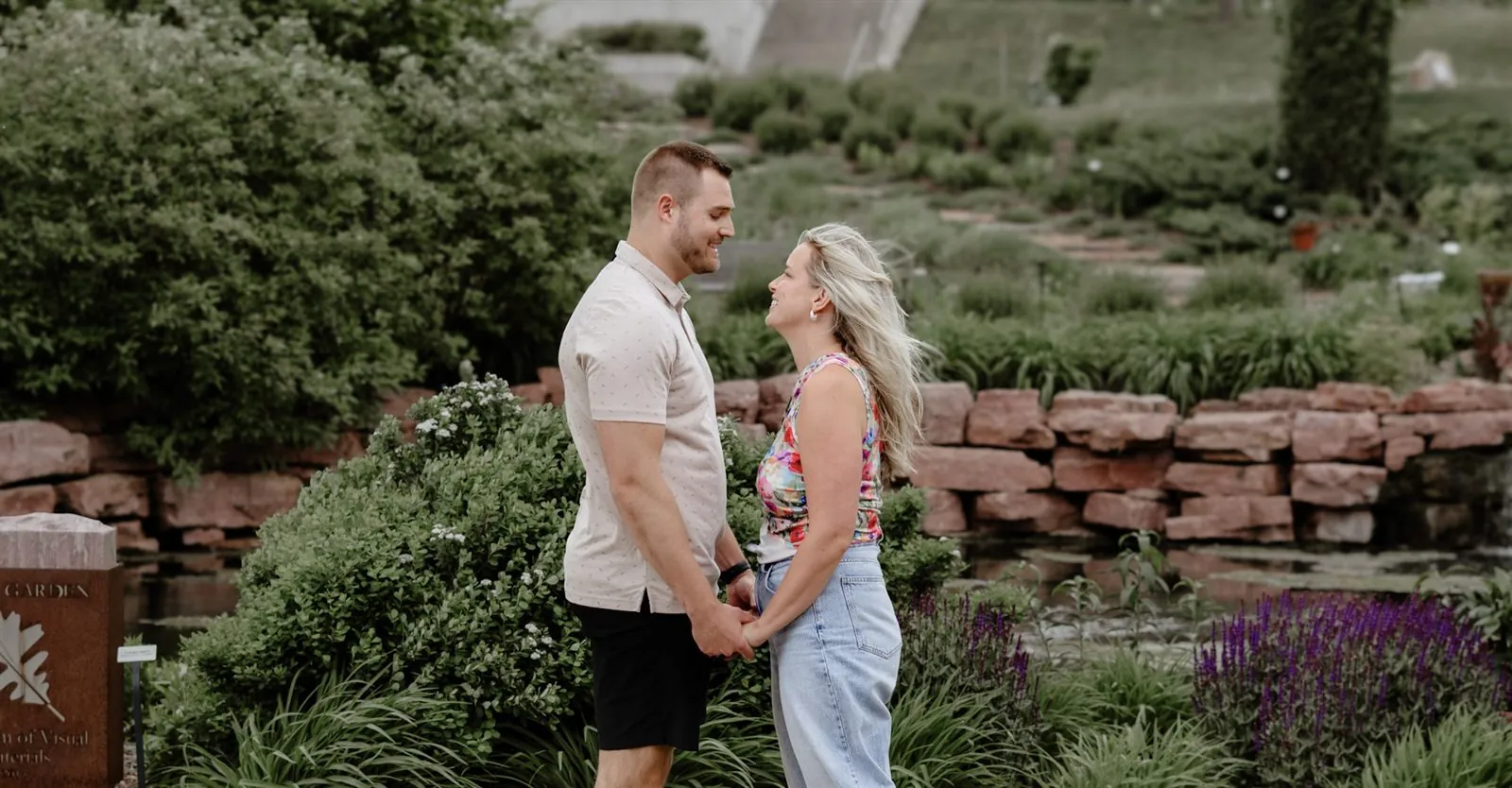 Couple standing face to face holding hands by a stone waterfall