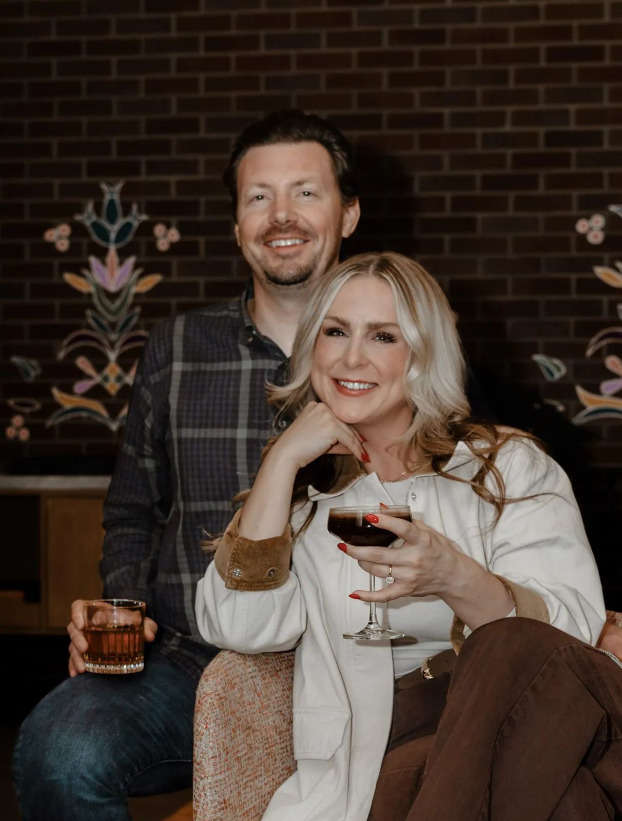 Couple enjoying cocktails together at a cozy brick-walled bar
