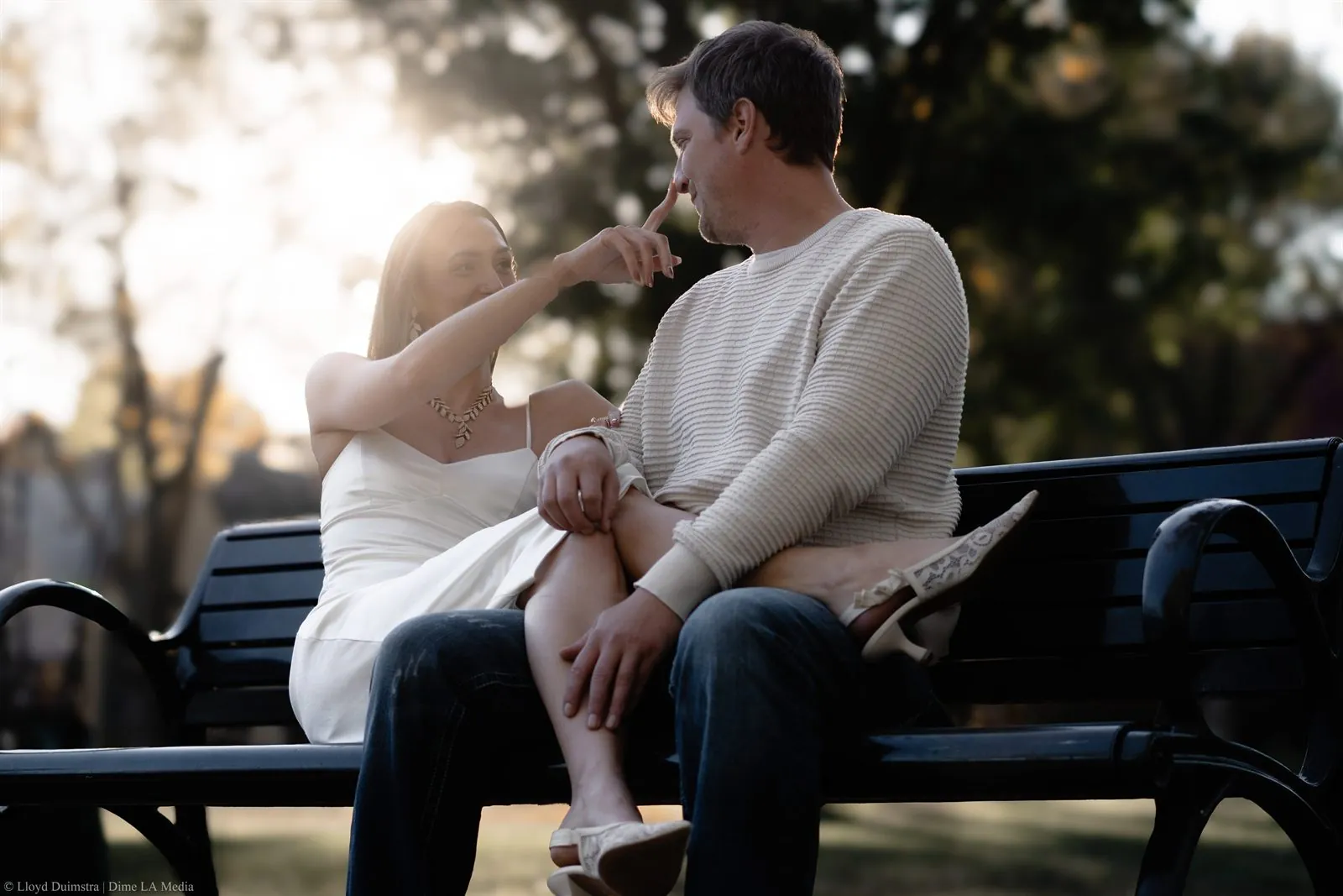 Woman playfully touching her fiance's nose in golden autumn light