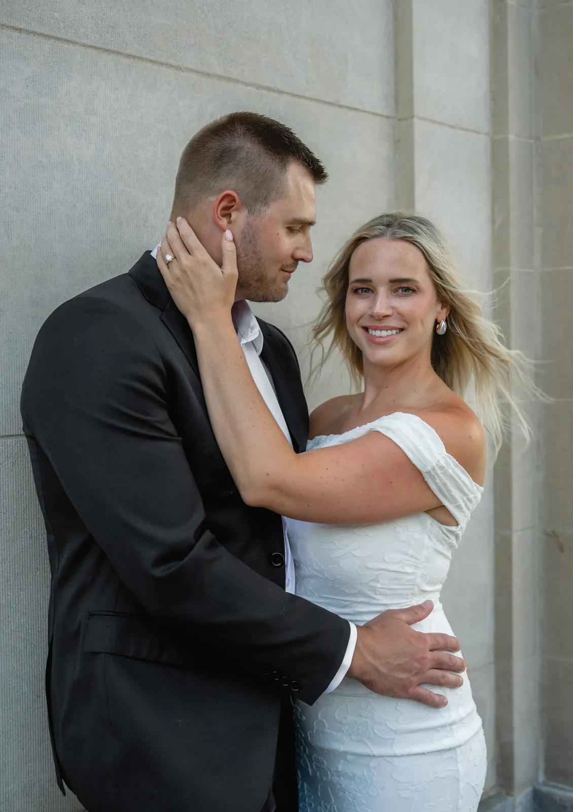 Woman smiling at the camera with her hand on her fiance's cheek