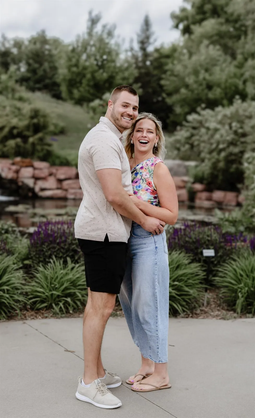 Engaged couple laughing together in a summer garden