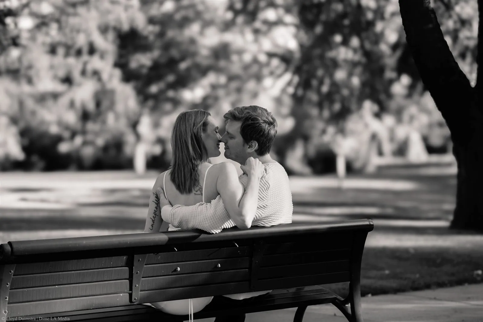 Black and white photo of a couple leaning close together on a park bench