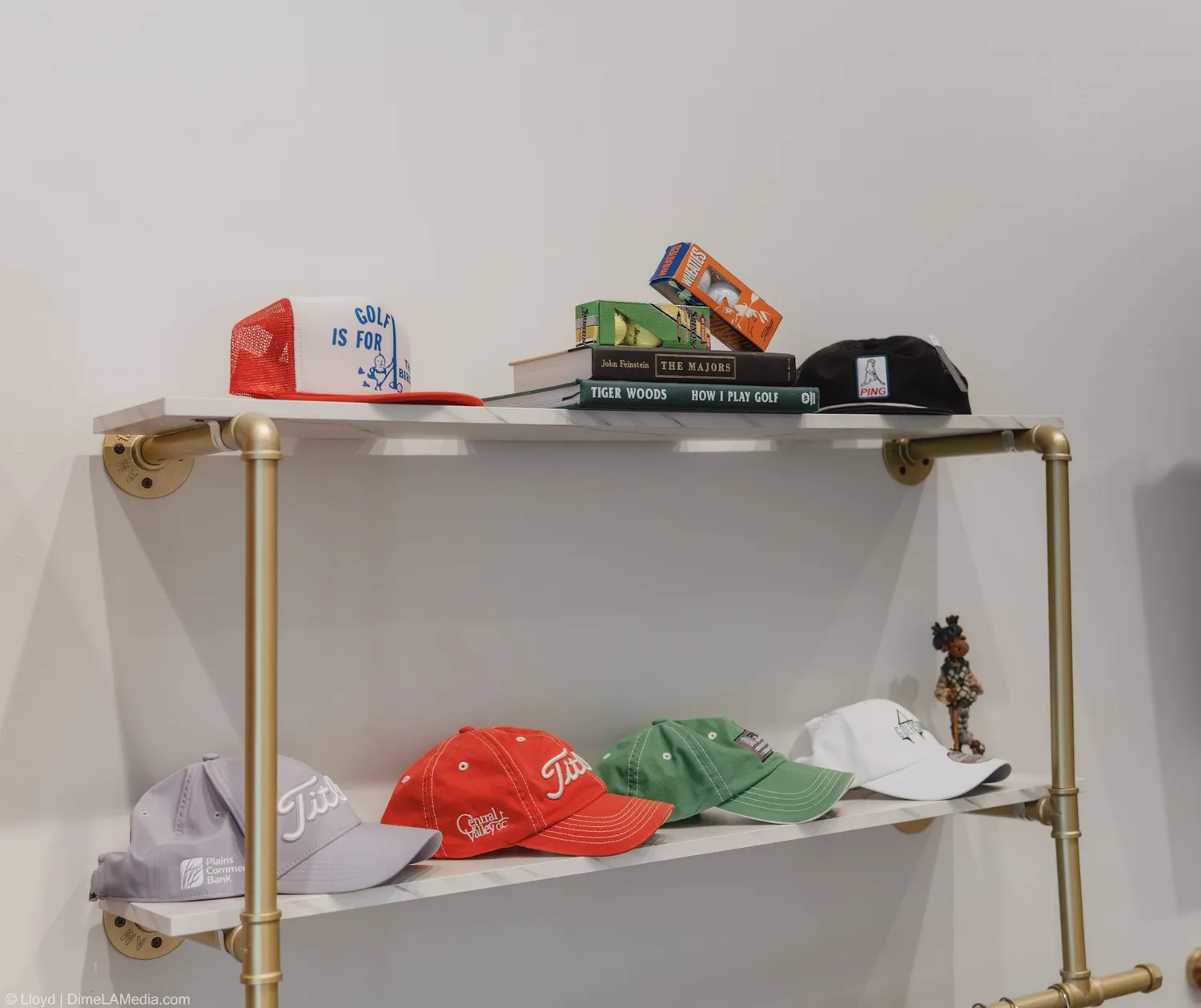 Brass shelving with hats, books, and golf goods inside Final Drive