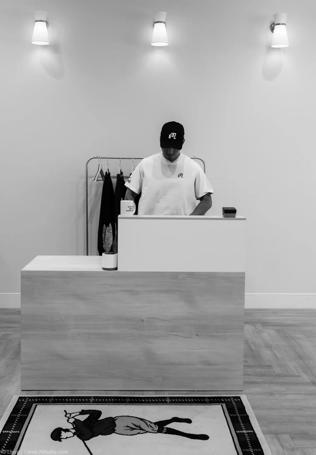 Black and white frame of Peter Gotner at the Final Drive checkout counter above a tiled golfer mosaic