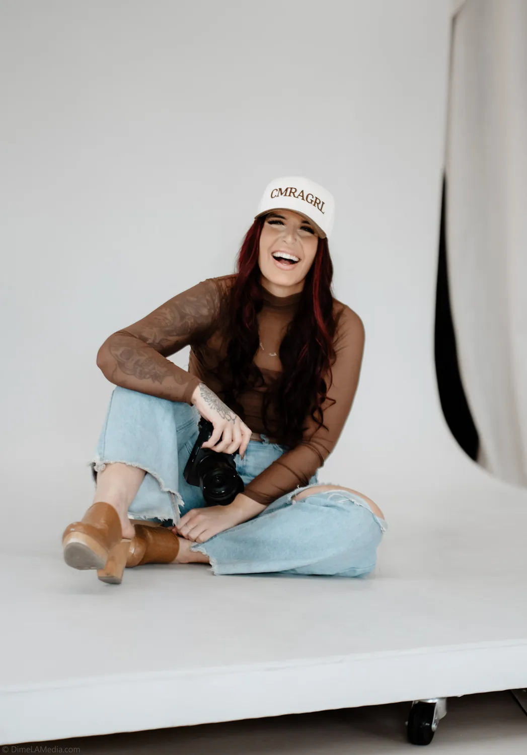 Jade laughs holding her camera during a studio personal branding session in Sioux Falls