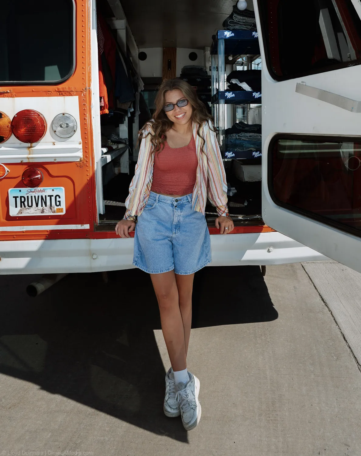 Maddie Theisen leans on the tailgate of the True Vintage bus in the afternoon sun