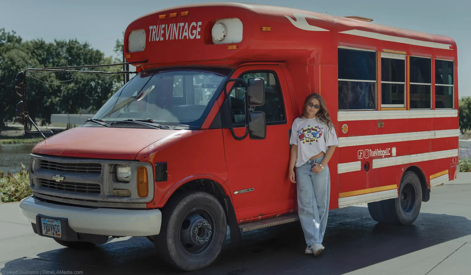 Maddie Theisen stands beside the full True Vintage bus, a red vintage bus turned mobile clothing shop in Sioux Falls