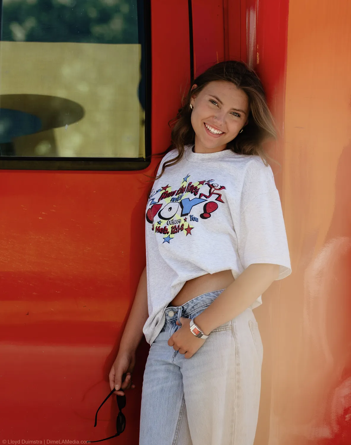 Maddie Theisen laughs against the red side of the True Vintage bus