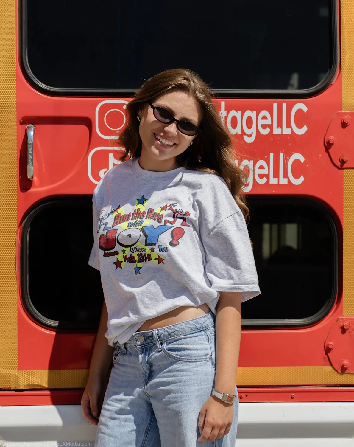 Maddie Theisen stands against the True Vintage bus with its painted social handles