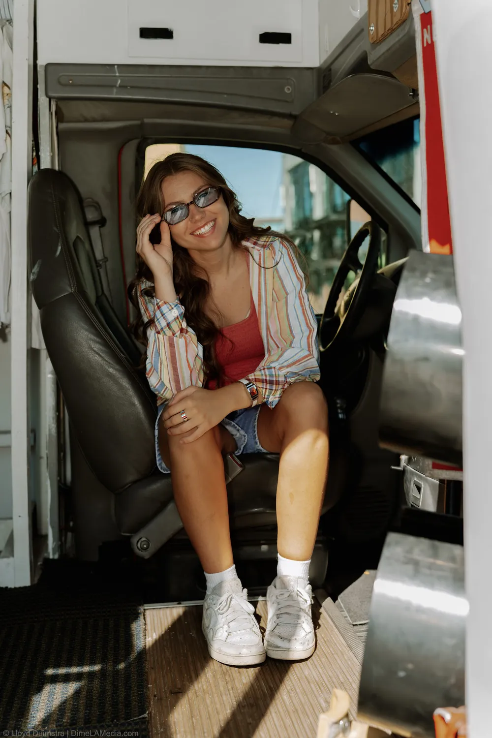 Maddie Theisen smiles from the doorway seat of her vintage clothing bus in Sioux Falls