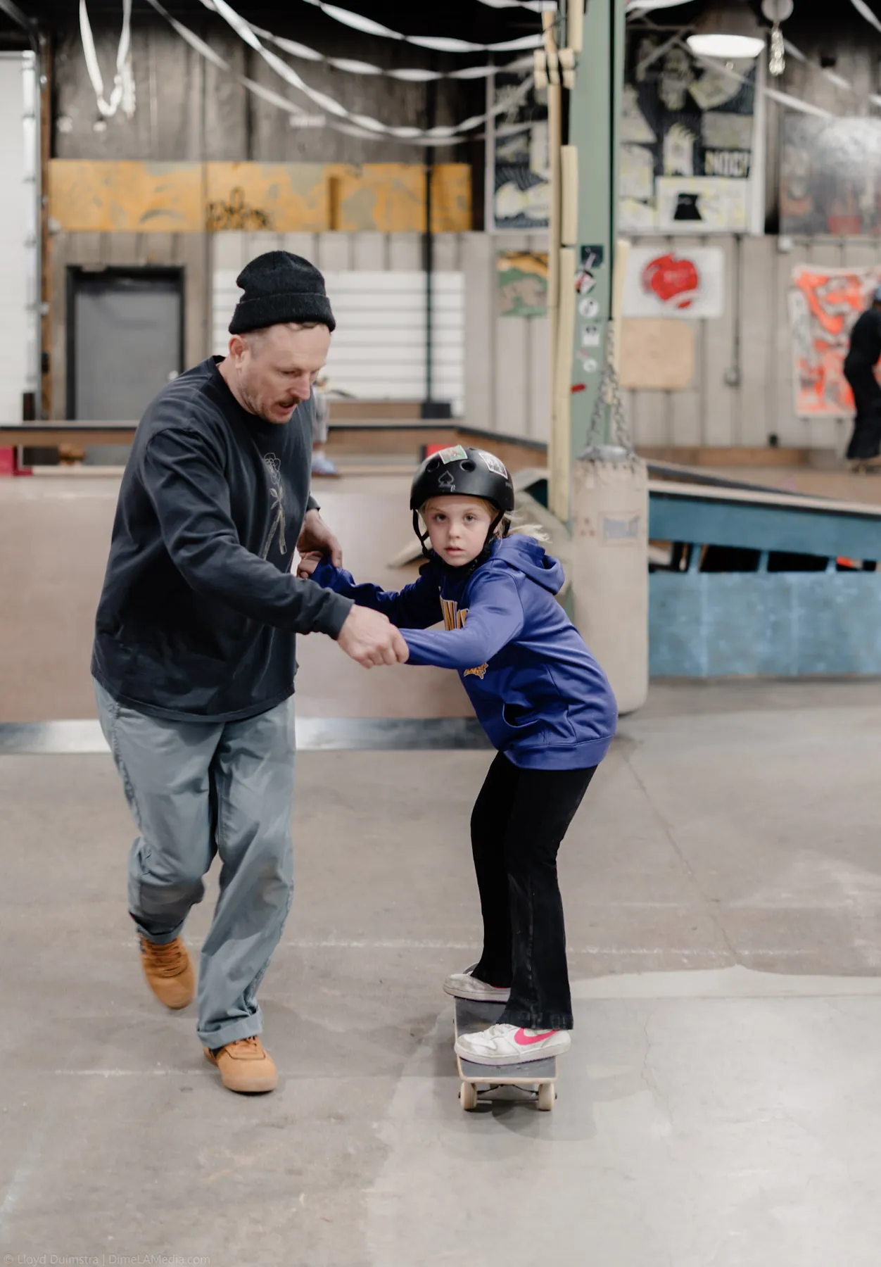 Coach steadying a young skater during an indoor lesson