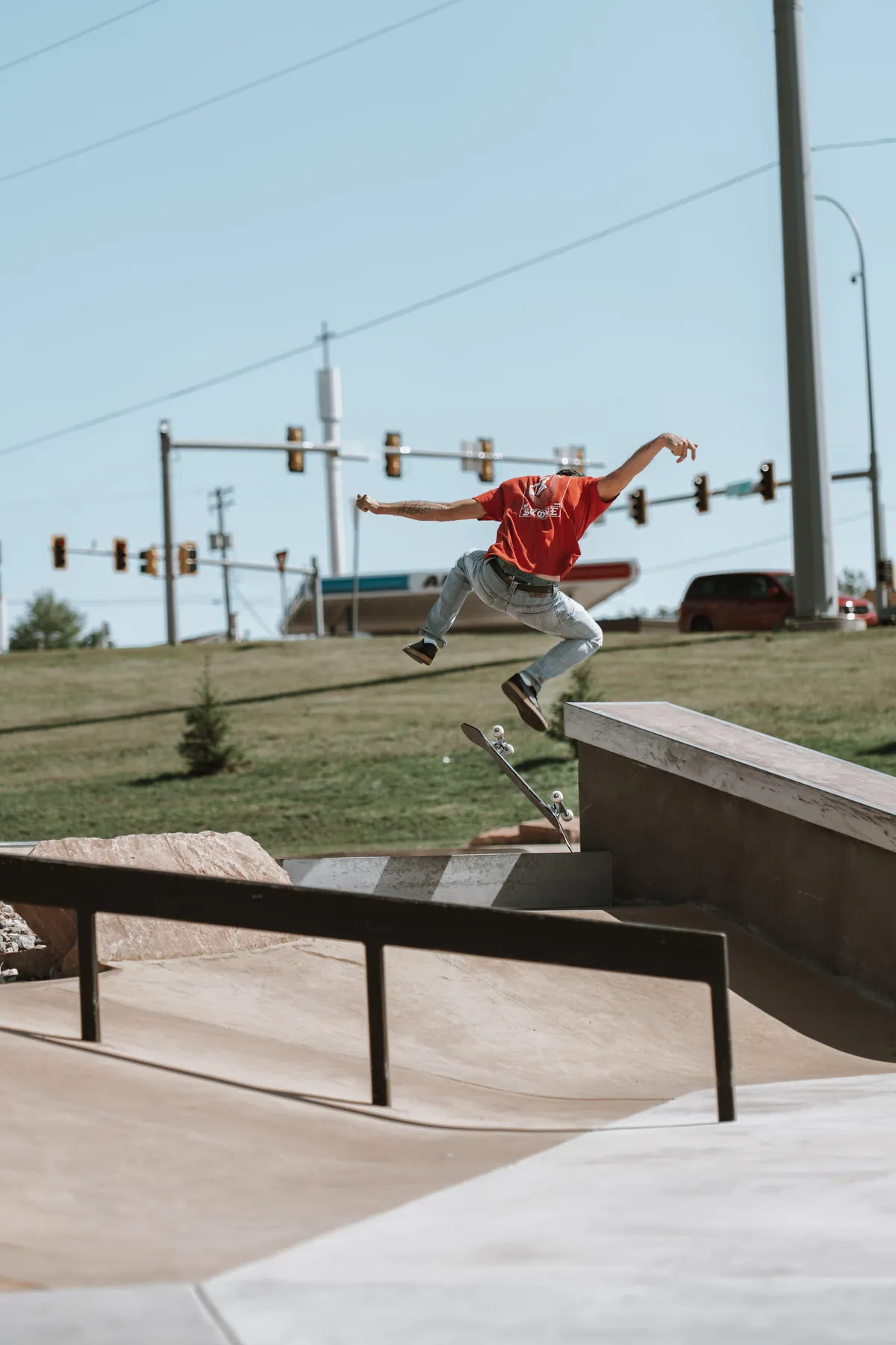 Skateboarder in red hitting a rail at golden hour