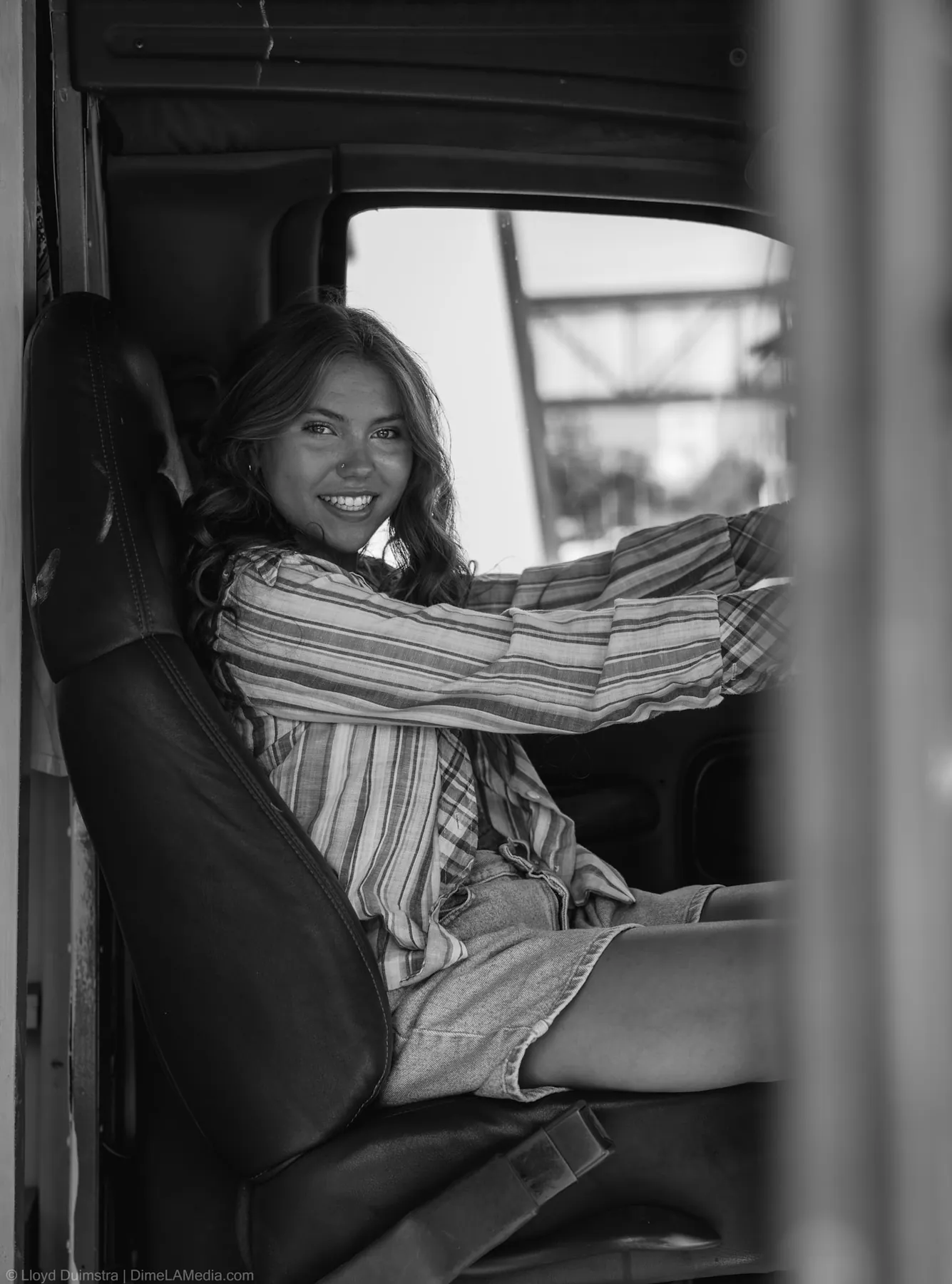 Black and white portrait of Maddie in the cab window of her bus