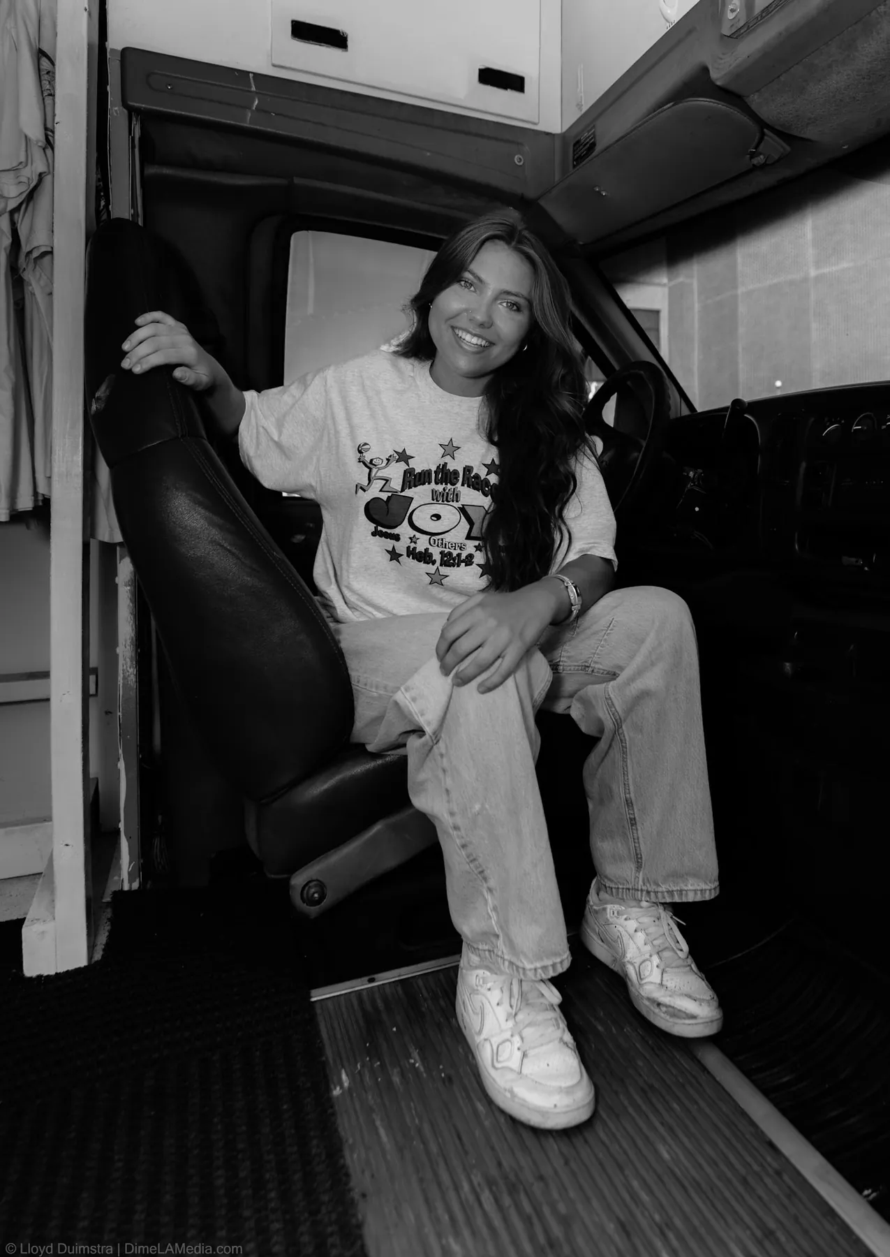 Black and white photo of Maddie seated inside the bus cab