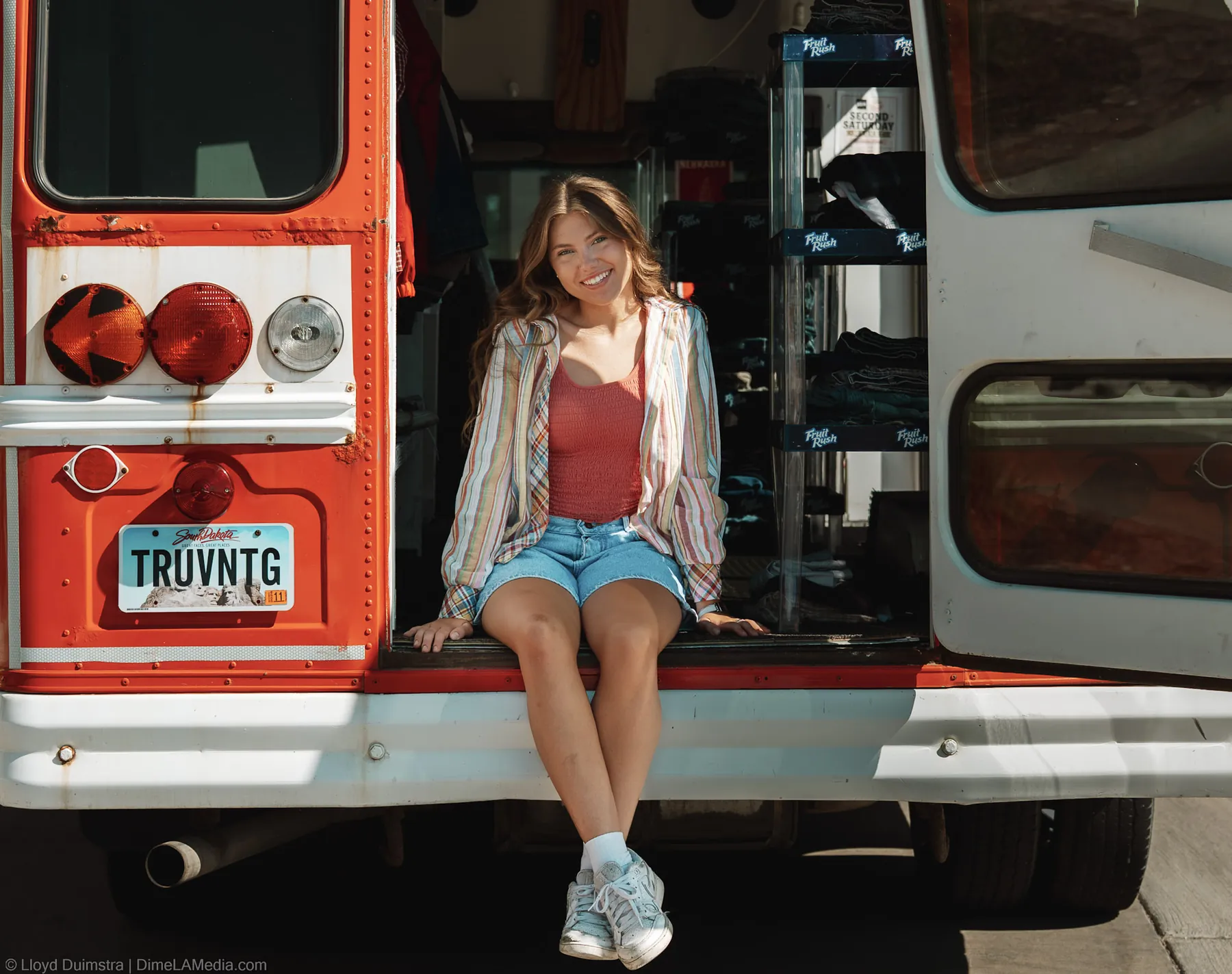 Maddie seated on the back bumper of the True Vintage bus