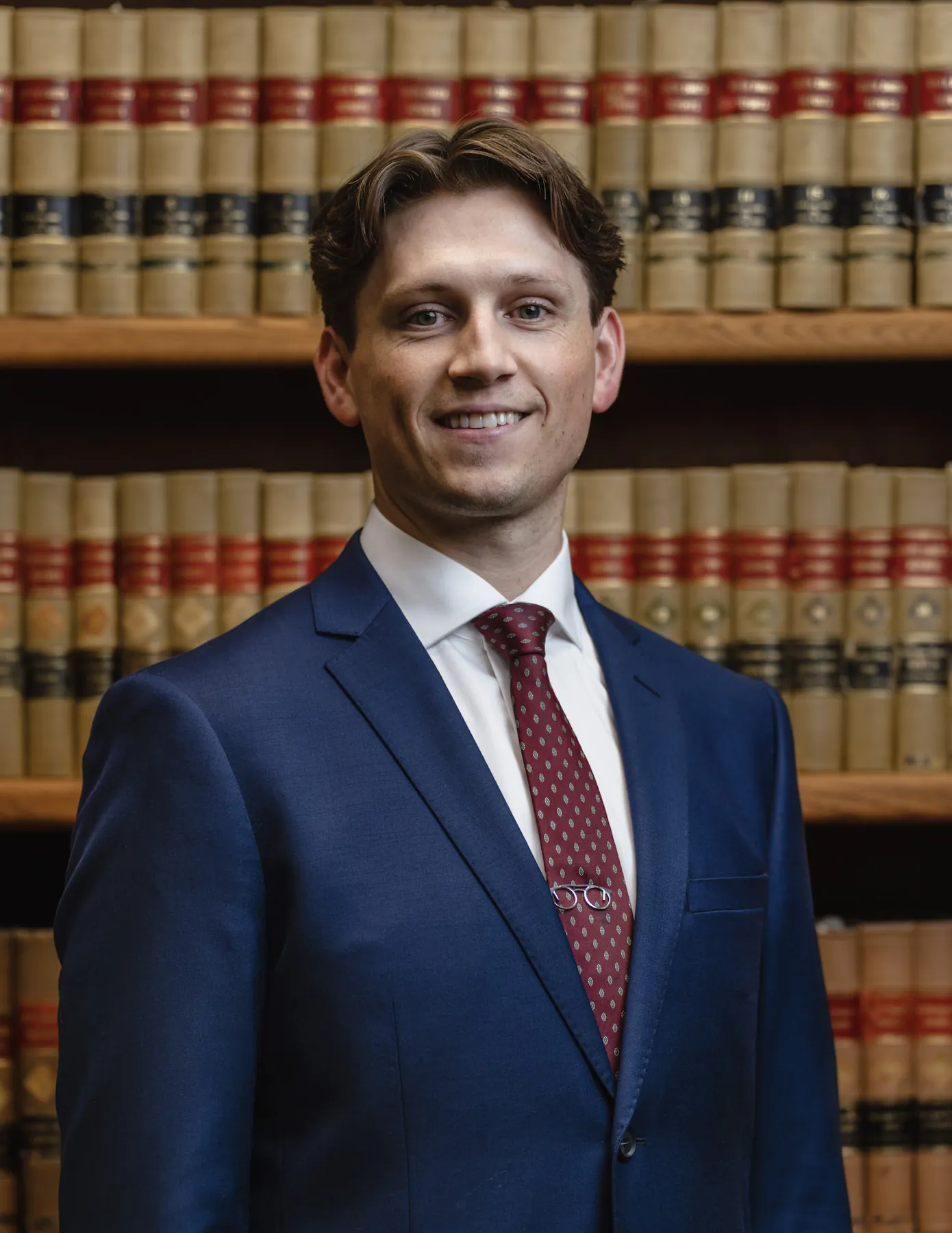 Attorney headshot in a navy suit before a law library wall, Sioux Falls SD