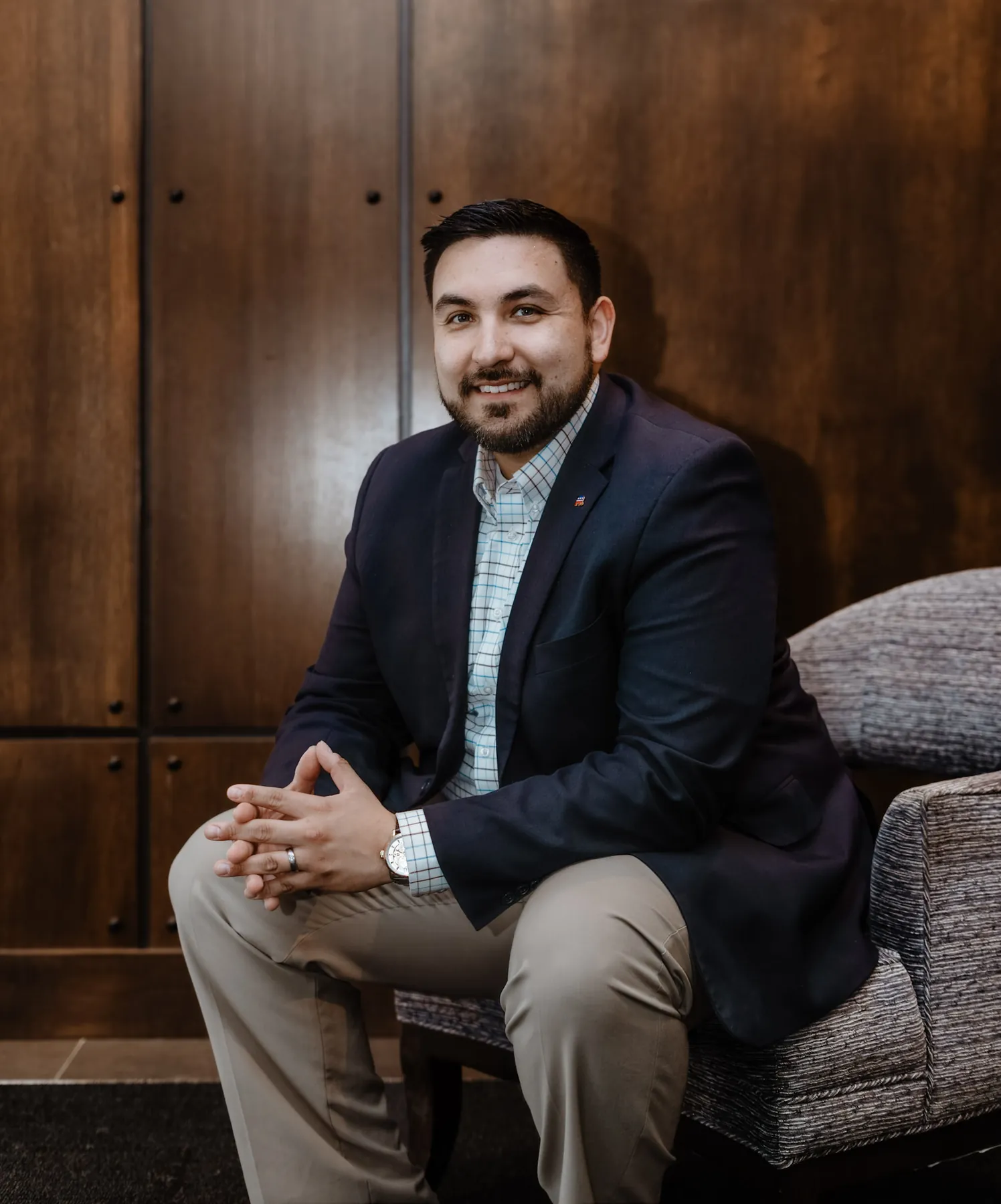 Tyler Tordsen seated business portrait against warm wood paneling