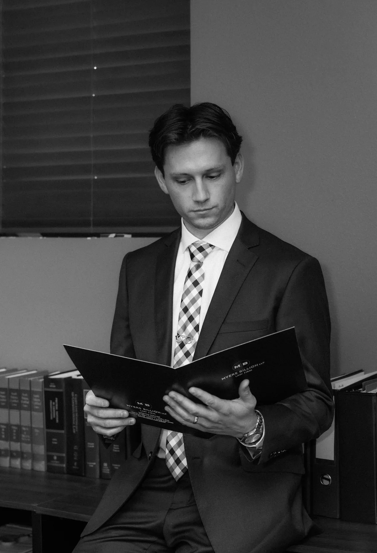 Black and white environmental portrait of an attorney reviewing a file