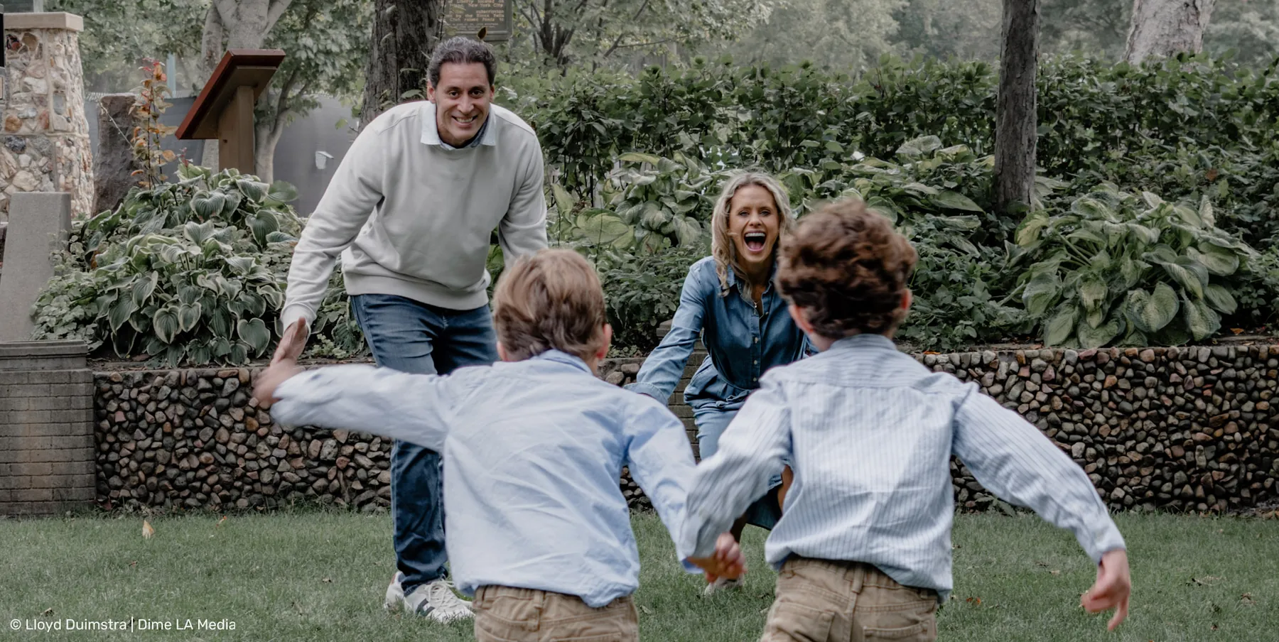 Parents chasing their boys across the park lawn