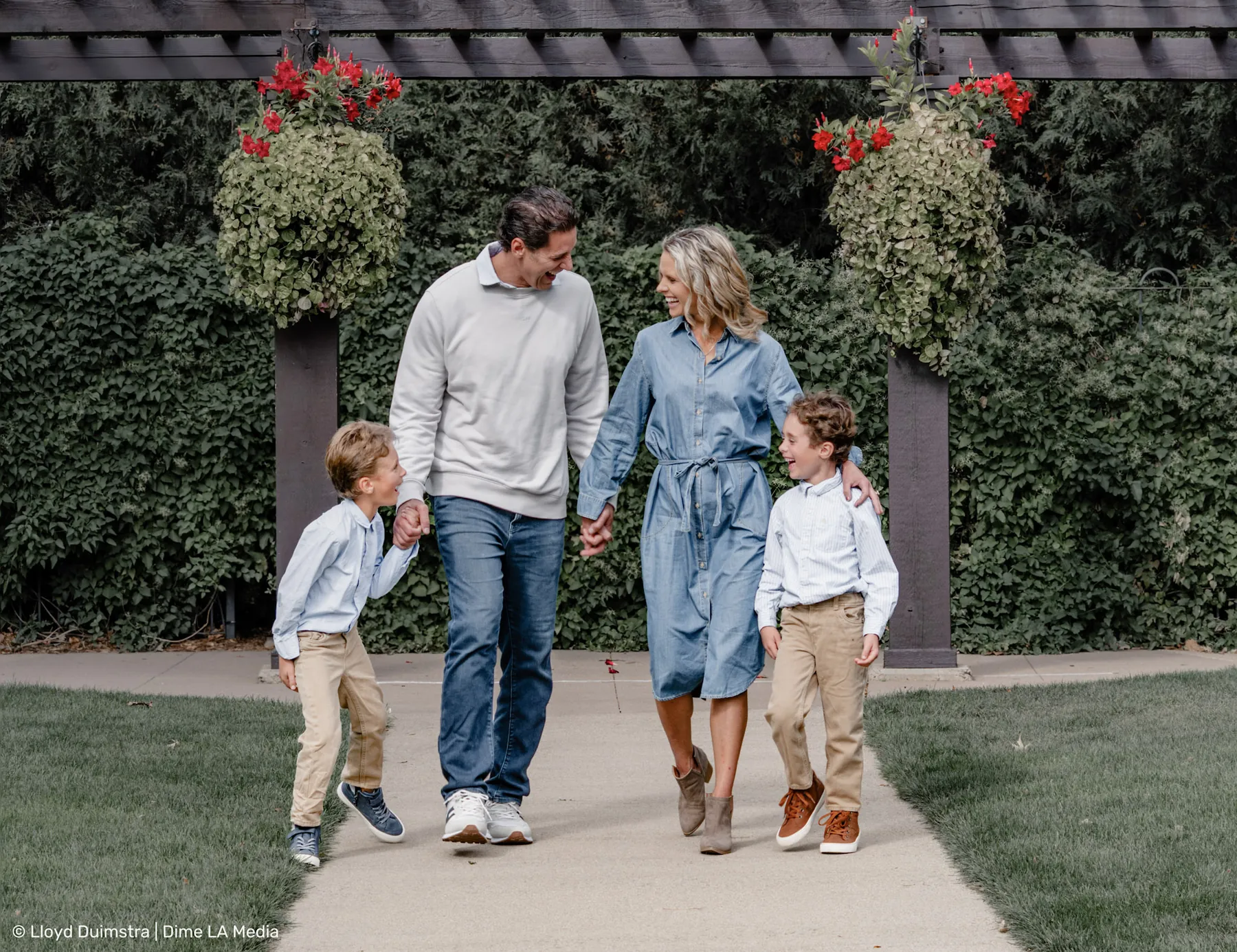 Family strolling beneath a garden pergola with hanging flowers