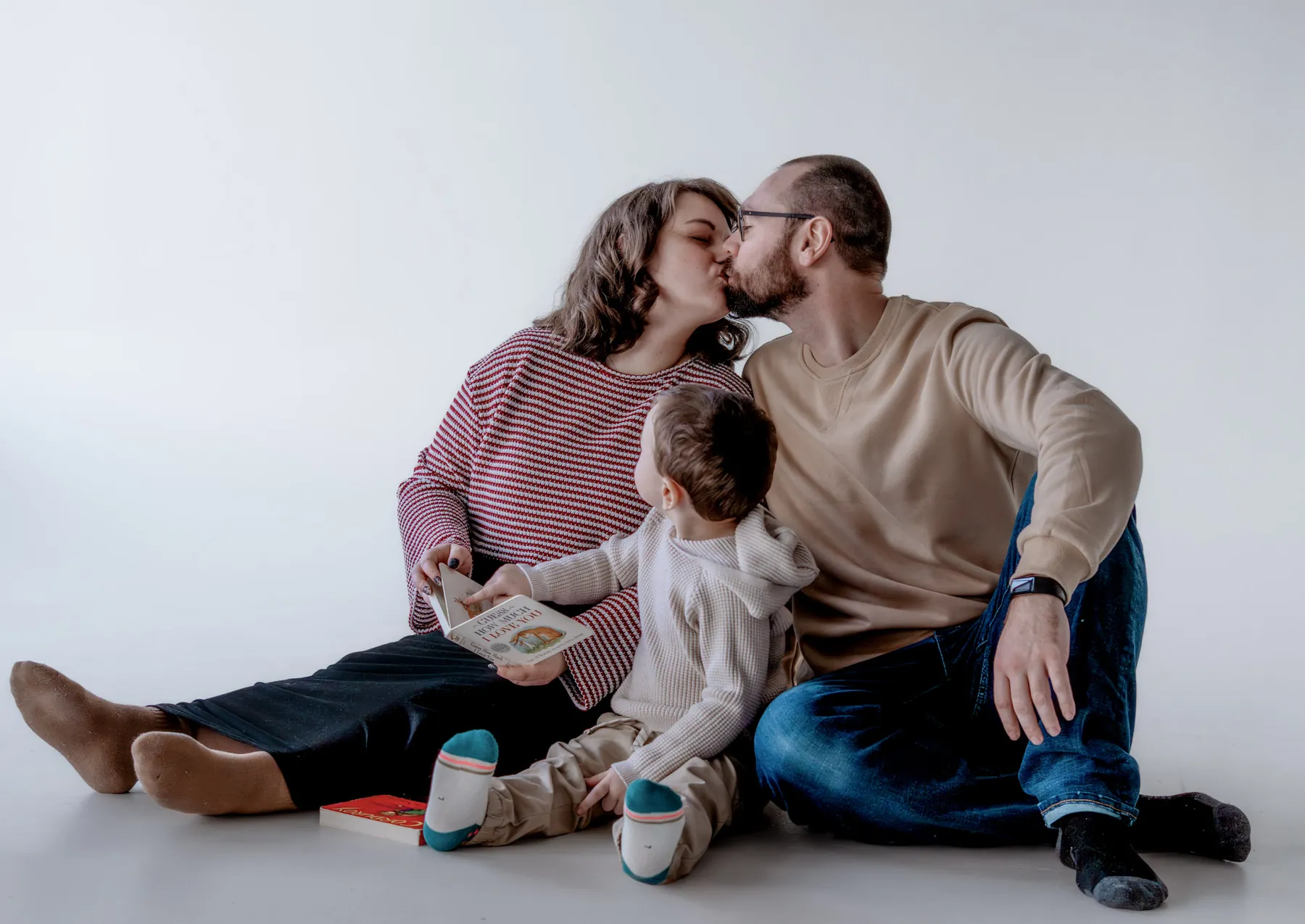 Parents kissing while their son plays at their feet