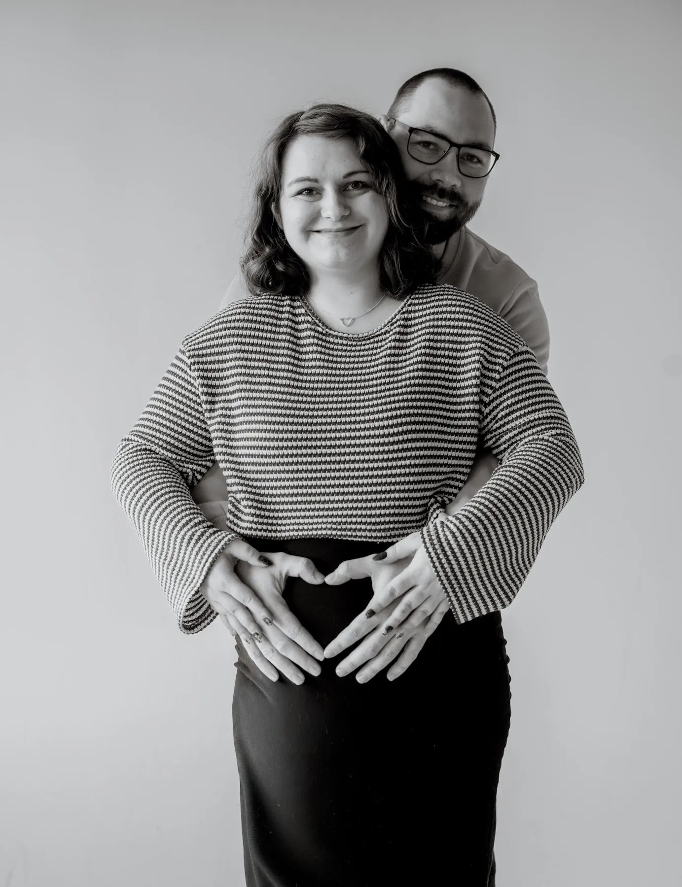 Heart hands over the baby bump, black and white maternity detail