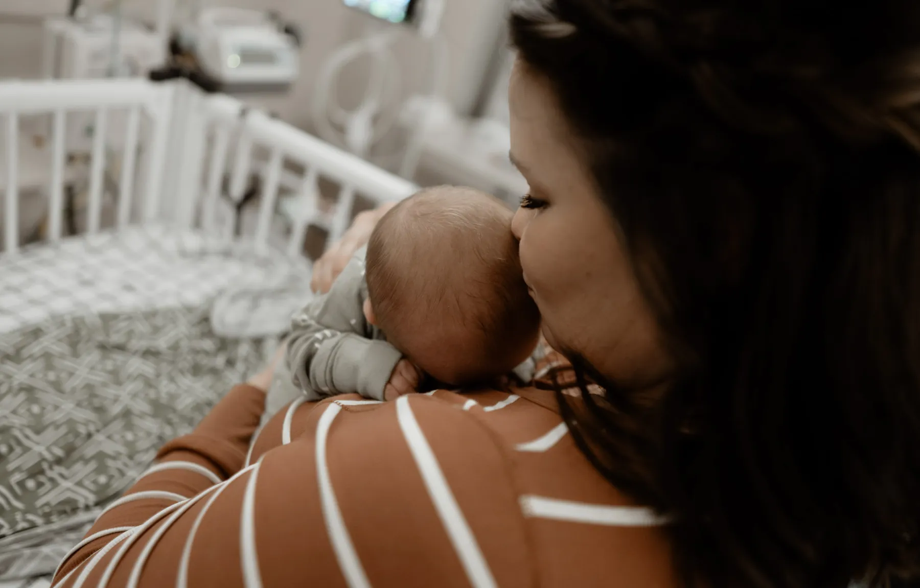 Mom holding her newborn by the NICU window