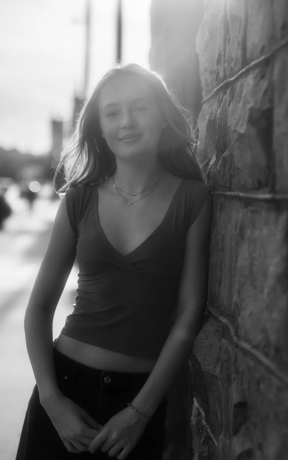 Black and white senior portrait of Scout against a stone wall on a downtown Sioux Falls street