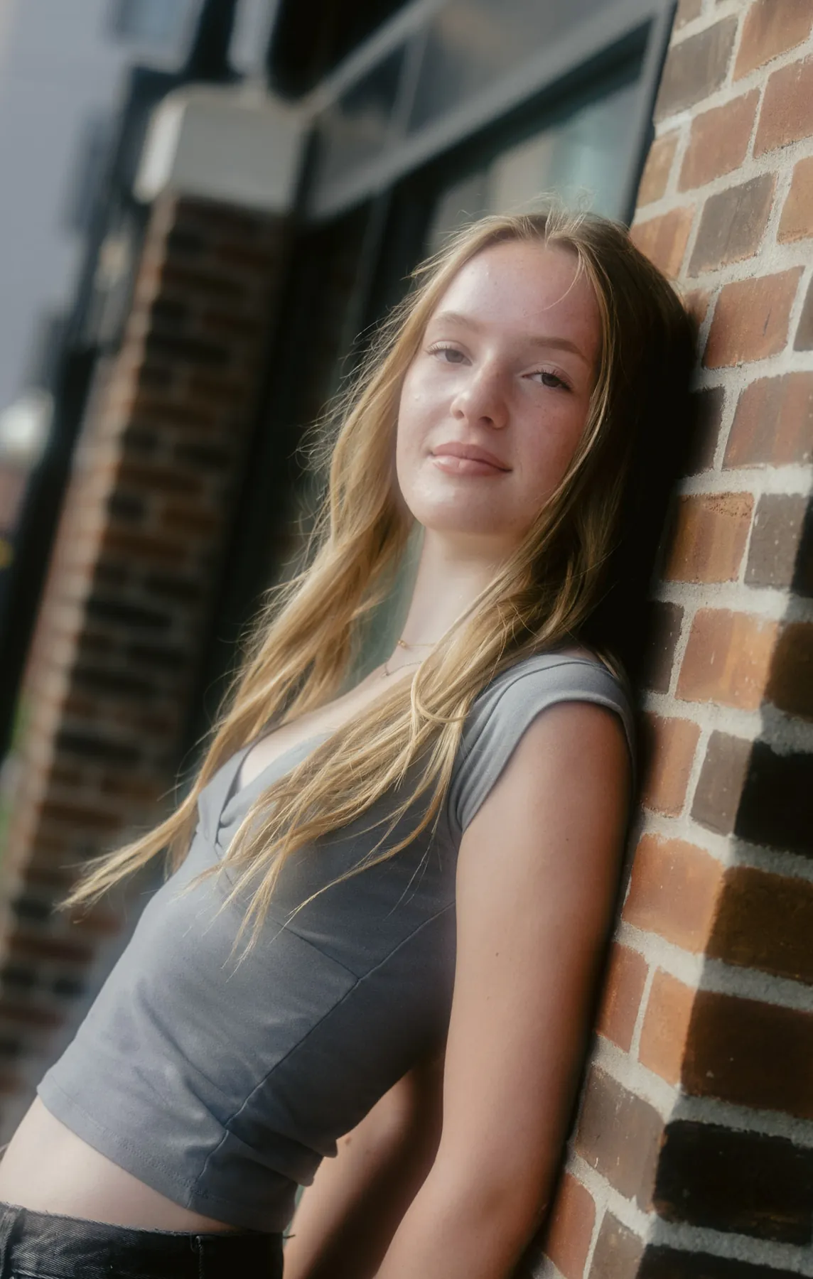 Film-toned senior portrait against a warm brick wall, Sioux Falls SD