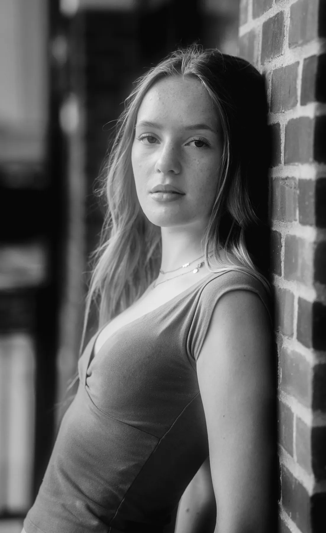 Black and white senior portrait against brick, downtown Sioux Falls