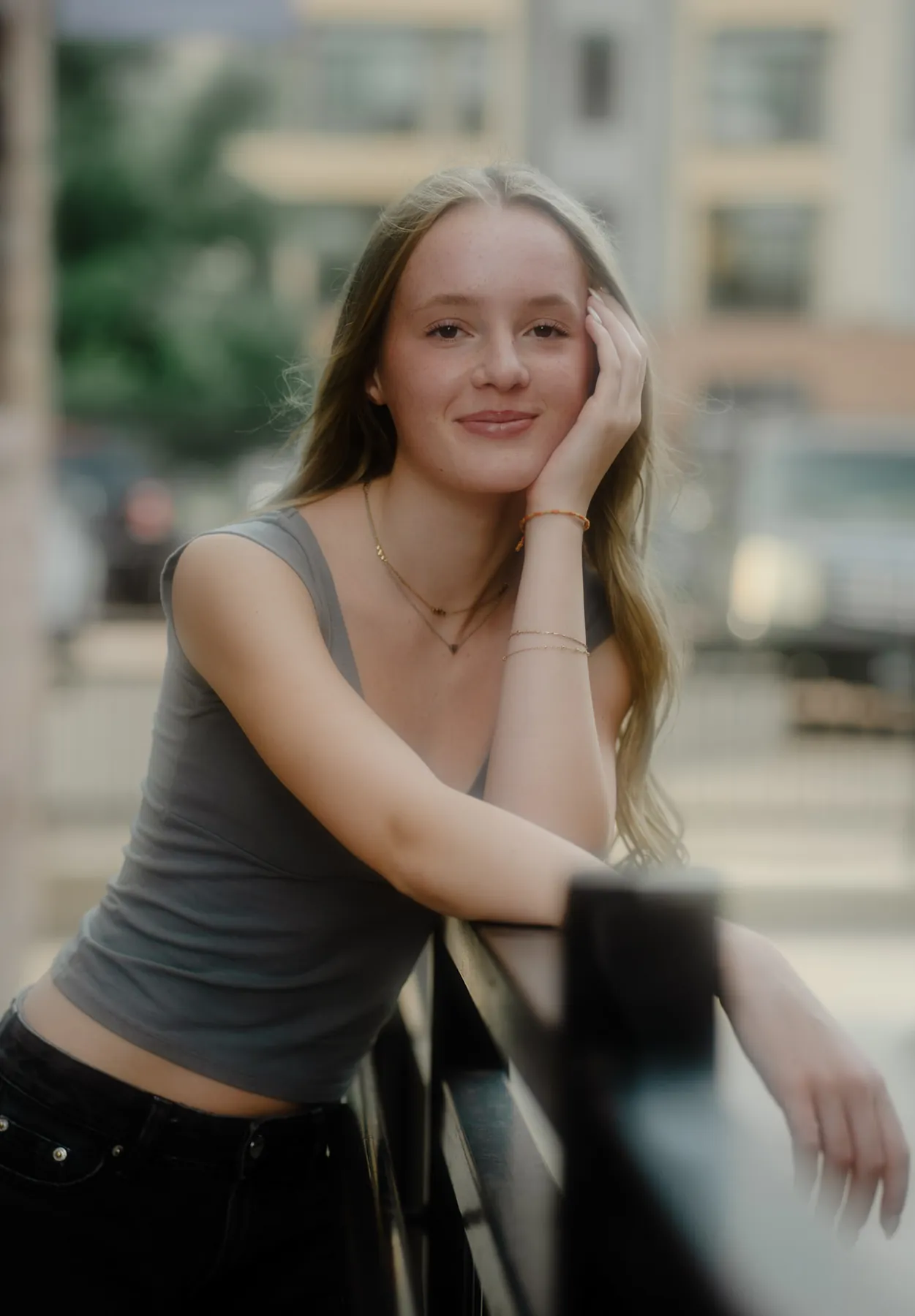 Scout smiling at a downtown railing with the city blurred behind her