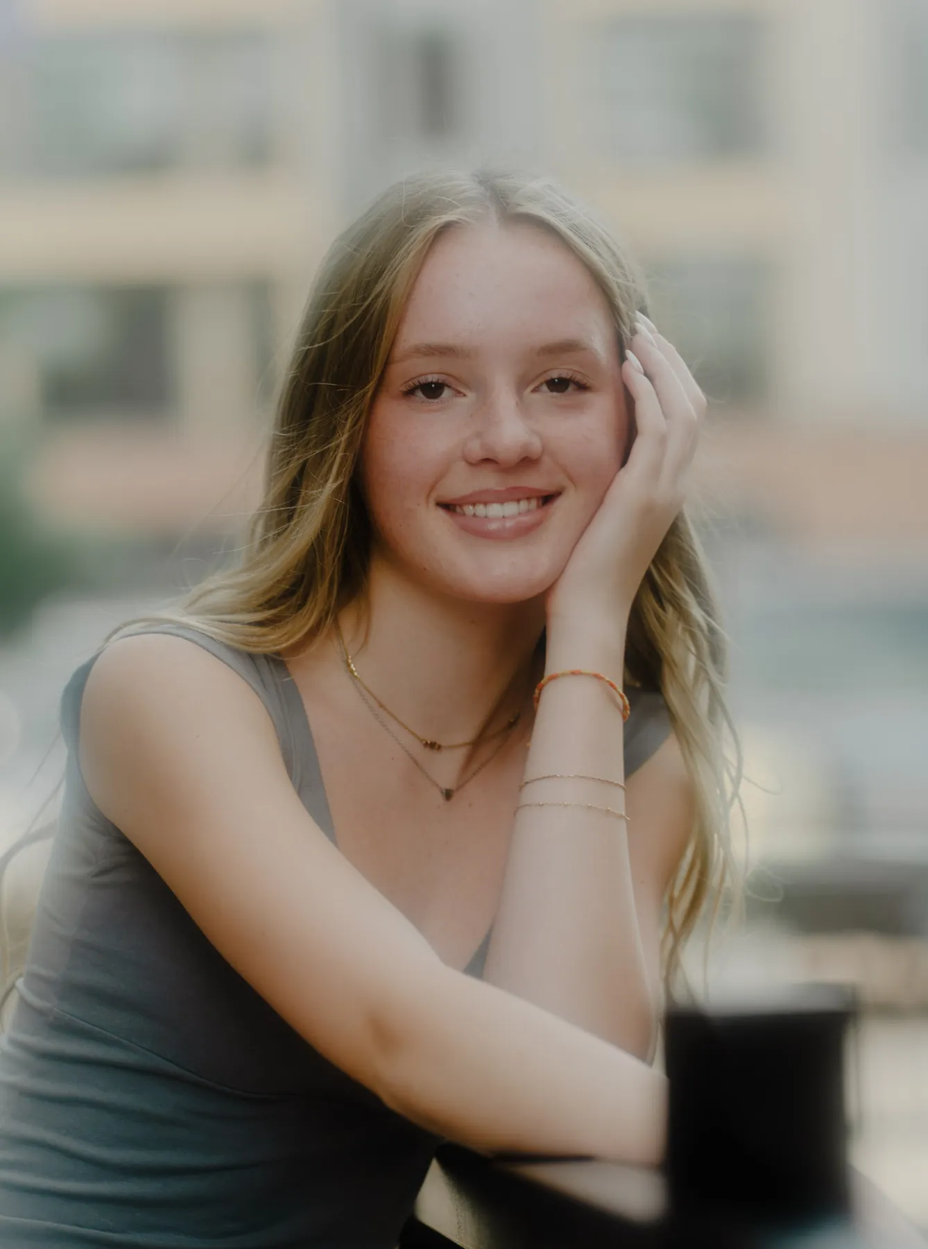 Scout resting her chin on her hand at a downtown railing, warm film-toned senior portrait