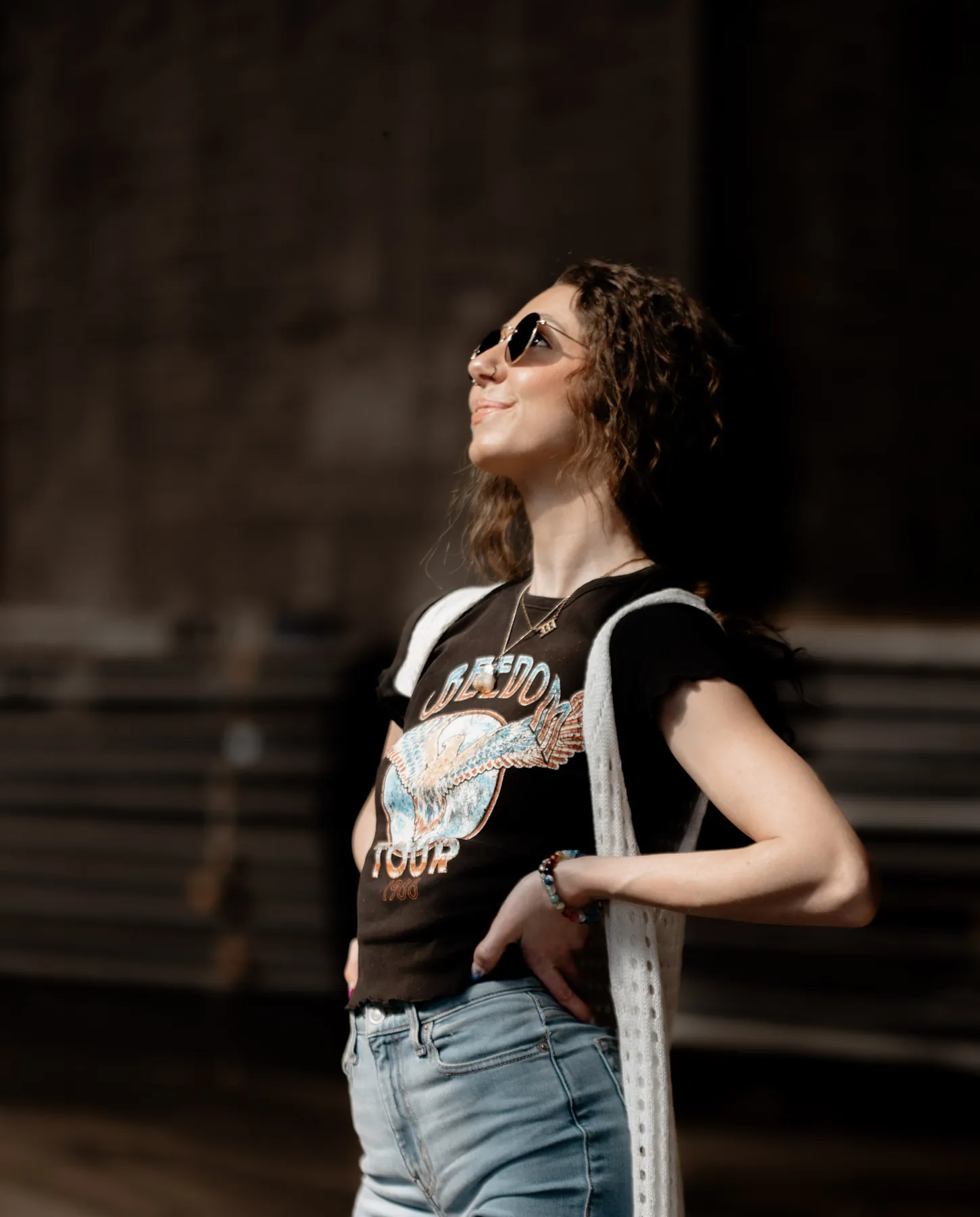 Portrait of a woman in a band tee inside a sunlit warehouse