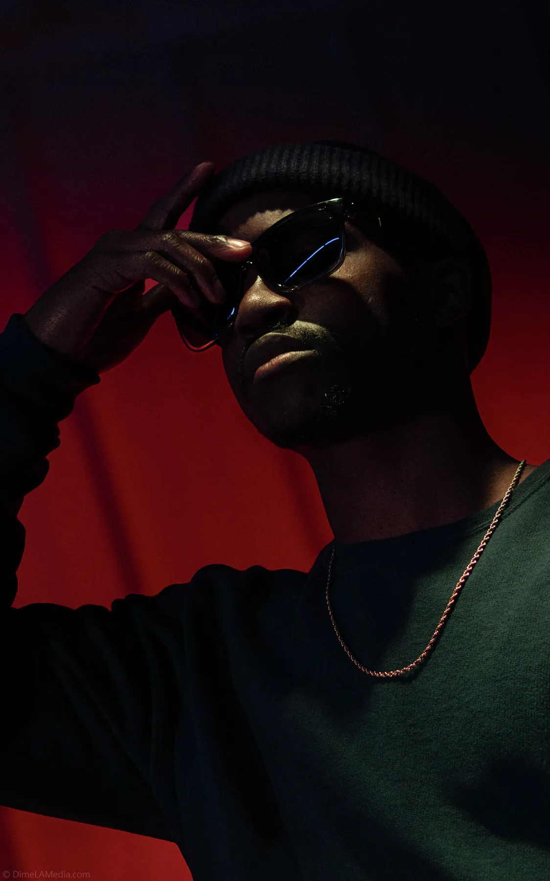 Low-key studio portrait in sunglasses with red rim light