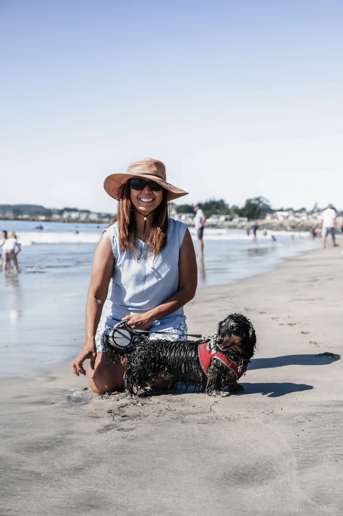 Beach portrait of a woman in a sun hat with her dog, golden light